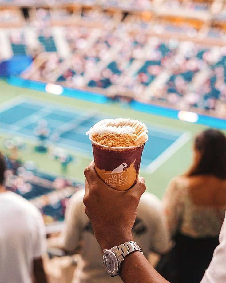 Copa de açaí OAKBERRY con vista aérea de un estadio de tenis lleno